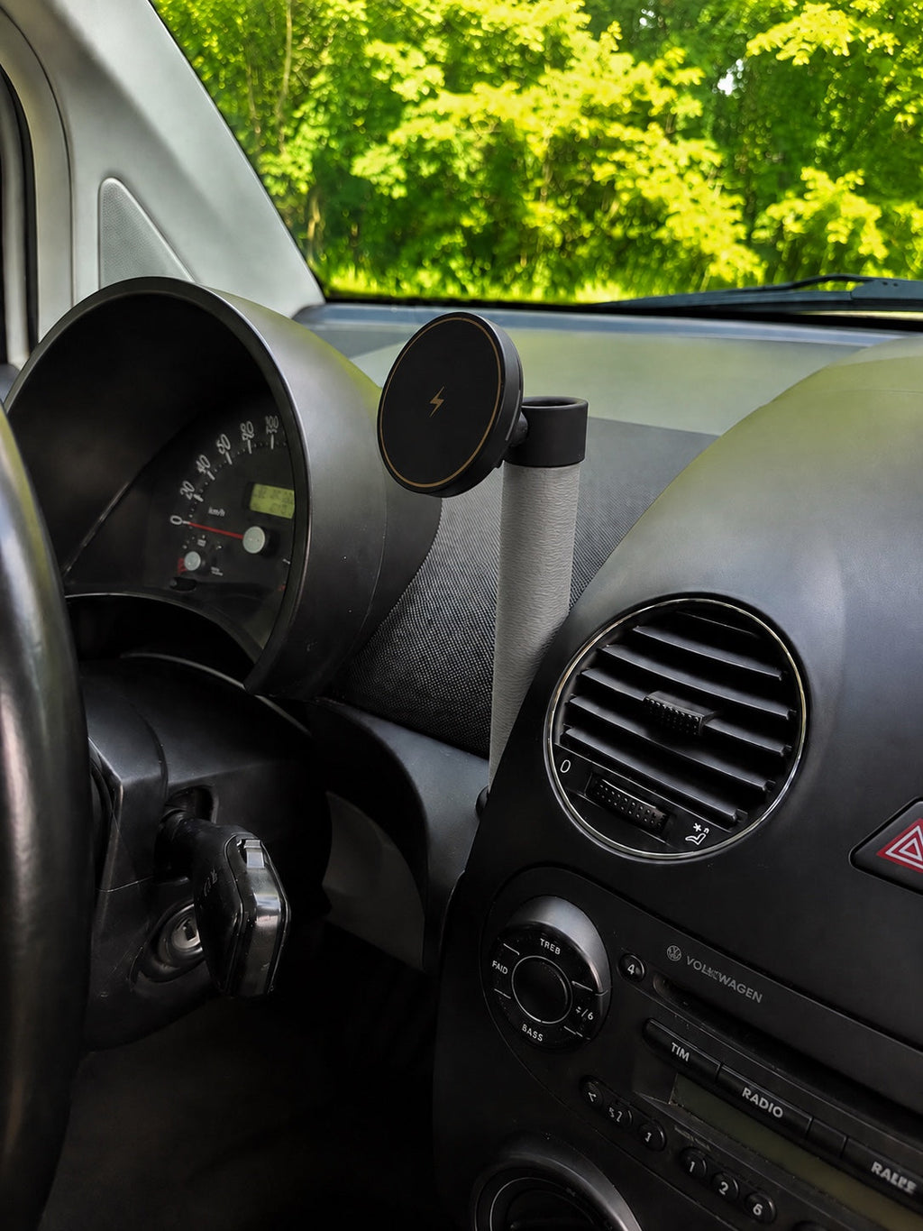 Grey MagSafe wireless phone charger mount installed in Volkswagen New Beetle dashboard vase holder
